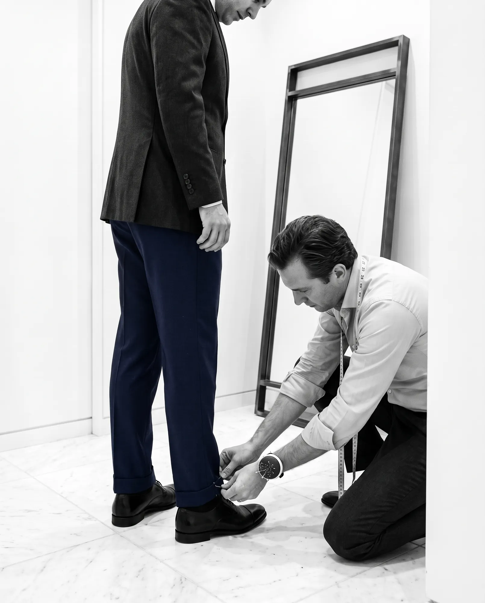 Tailor pinning trousers in the fitting room